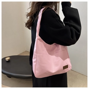 Gros plan du sac à bandoulière rose avec étiquette en cuir pour un style décontracté