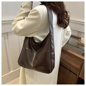 Détail d'un grand sac fourre-tout en cuir PU marron foncé porté à l'épaule par un mannequin