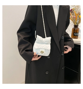 Close-up of white quilted mini bag with oversized bow and golden chain strap for women