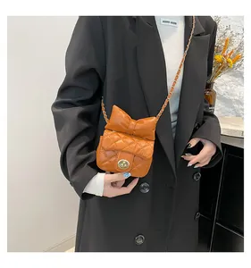 Close-up of orange quilted crossbody bag with oversized bow and gold chain strap