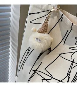 Dettaglio di un simpatico ciondolo in peluche con berretto su borsa shopper in tela
