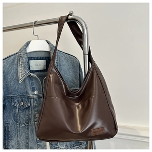 Détail d'un sac hobo en cuir PU marron avec étiquette cousue sur la partie avant