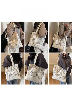 Viste multiple di una borsa tote in tela beige con graffiti neri e ciondolo di peluche