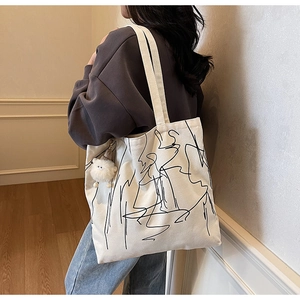 Dettaglio della borsa tote in tela bianco avorio con arte astratta e ciondolo a pecora