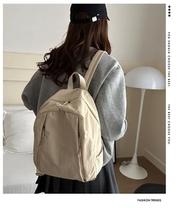 Detail view of beige canvas backpack with multi-zipper compartments in home setting