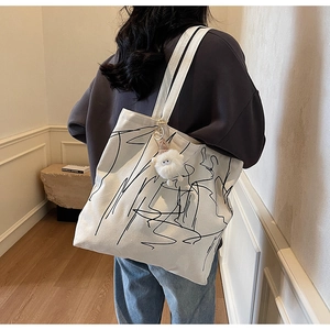 Dettaglio della borsa tote in tela bianca con arte astratta e ciondolo di peluche