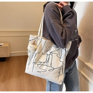 Dettaglio della borsa tote in tela con arte astratta e ciondolo in peluche bianco