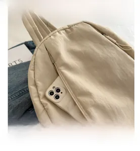 Detail view of the side zipper pocket on a beige nylon backpack for small item storage