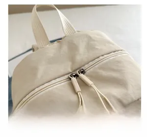 Detail of smooth double zipper with cord pulls on a beige minimalist backpack