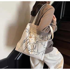 Dettaglio borsa tote in tela con linee astratte e ciondolo a forma di pecora di peluche