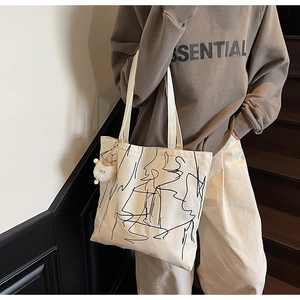 Dettaglio della borsa tote in tela bianca con stampa artistica astratta e ciondolo peluche