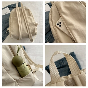 Detail view of cream nylon backpack featuring hidden side zipper and elastic pockets