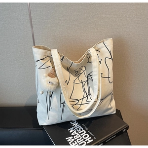 Dettaglio della borsa tote in tela con linee astratte e ciondolo a forma di pecora