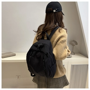 Close-up of black nylon backpack featuring textured fabric and dual front zipper pockets