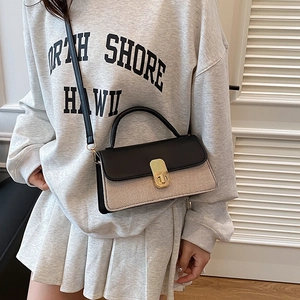 Sac bandoulière beige tissé avec cuir noir et fermoir doré porté par un mannequin