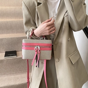 Chic beige canvas box bag with vibrant pink leather trim and adjustable crossbody strap