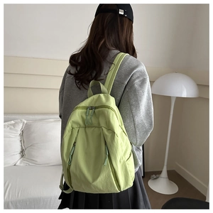 Close-up of light green nylon backpack with multiple zippers and adjustable straps