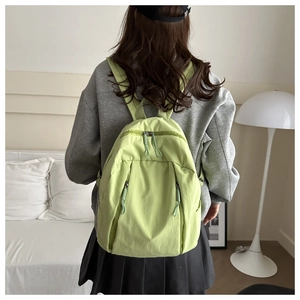 Detail of light green nylon backpack with multi-zipper pockets and minimalist design