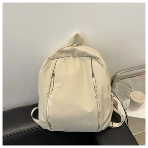 Detailed view of cream nylon backpack with vertical zipper pockets on a modern sofa