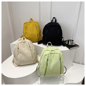 Minimalist nylon backpacks in yellow, black, beige, and green shown on a display stand