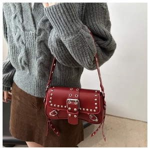 Close-up of red punk style bag with silver studs and eyelets on shoulder strap