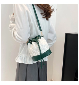 Detail of quilted bucket bag with green trim and drawstring closure on shoulder strap