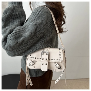 Detail of rivet-decorated beige PU leather bag with silver buckles and strap