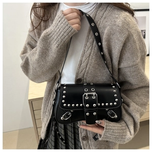 Close-up of black rivet shoulder bag with silver studs and metal buckle on the strap