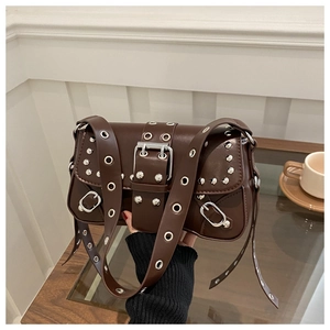 Close-up of dark brown punk bag featuring metallic silver eyelets and silver buckle