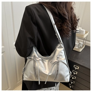 Détail du sac cabas argenté avec nœud décoratif et fermetures éclair verticales