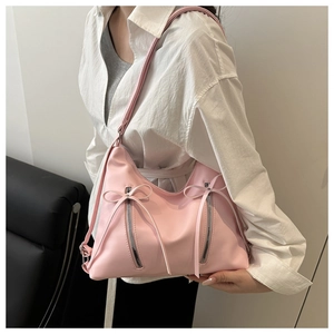 Close-up of pink PU leather shoulder bag with bow ribbons and double metal zippers
