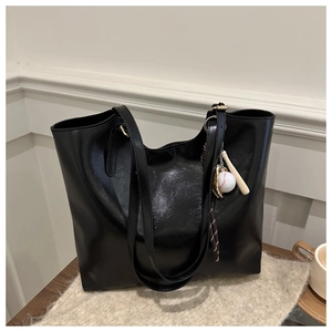 Detail of black glossy faux leather tote bag with unique baseball themed pendant charm