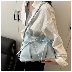 Detail of light blue bow tote bag with matte leather finish and decorative double zippers