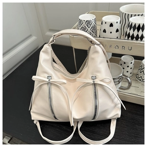Detail of cream PU leather handbag featuring decorative bows and dual silver zippers