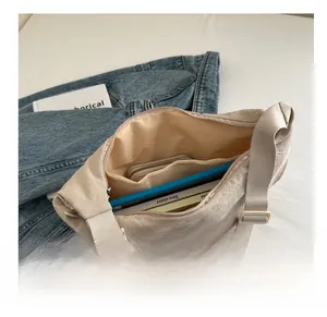 Macro view of spacious nylon crossbody bag interior with zip pocket and books