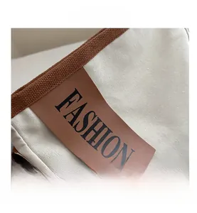 Detail of canvas tote bag with brown leather patch and FASHION lettering embroidery