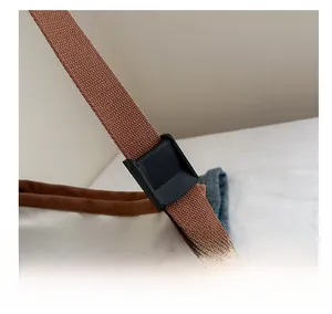Detail of adjustable brown woven shoulder strap with black buckle on canvas tote bag