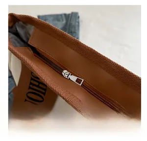 Detail of silver metal zipper and brown trim on a canvas tote bag with fashion print