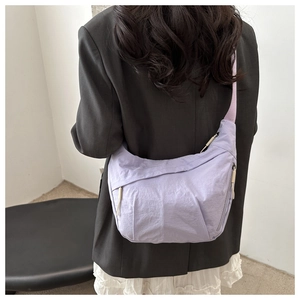 Detail view of a lavender nylon crescent crossbody bag with wide strap on a model