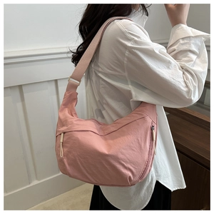 Detailed view of pink nylon crescent bag with adjustable strap and front zipper