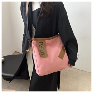 Detail view of pink canvas tote bag with brown trim and fashion patch for daily use