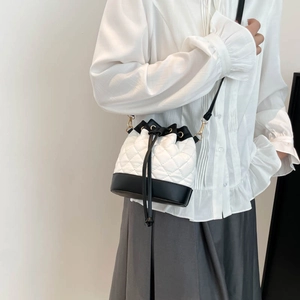 Quilted bucket bag with contrast black trim and gold hardware on female model