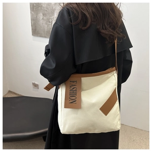 Detail of canvas tote bag with brown contrast trim and hanging fashion leather tag