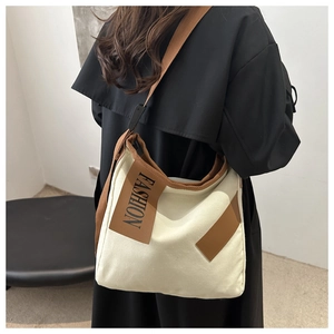 Détail du sac fourre-tout en toile crème avec bandoulières brunes et logo fashion