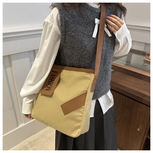 Detail of canvas tote bag showing the leather patchwork and fashion brand logo patch