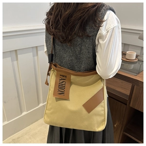 Détail du sac fourre-tout en toile beige avec finitions en cuir brun et étiquette