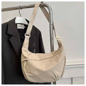 Detail of adjustable strap and crinkled nylon fabric on a beige crescent bag