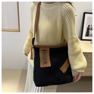 Detail of black canvas tote bag featuring brown leather patch with FASHION lettering