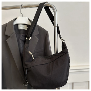 Detail of black nylon hobo bag with wide shoulder strap showing texture and drape