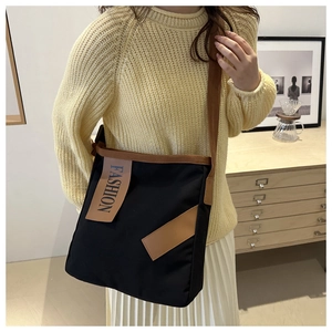 Détail d'un sac cabas noir en toile avec accents en cuir marron et étiquette Fashion